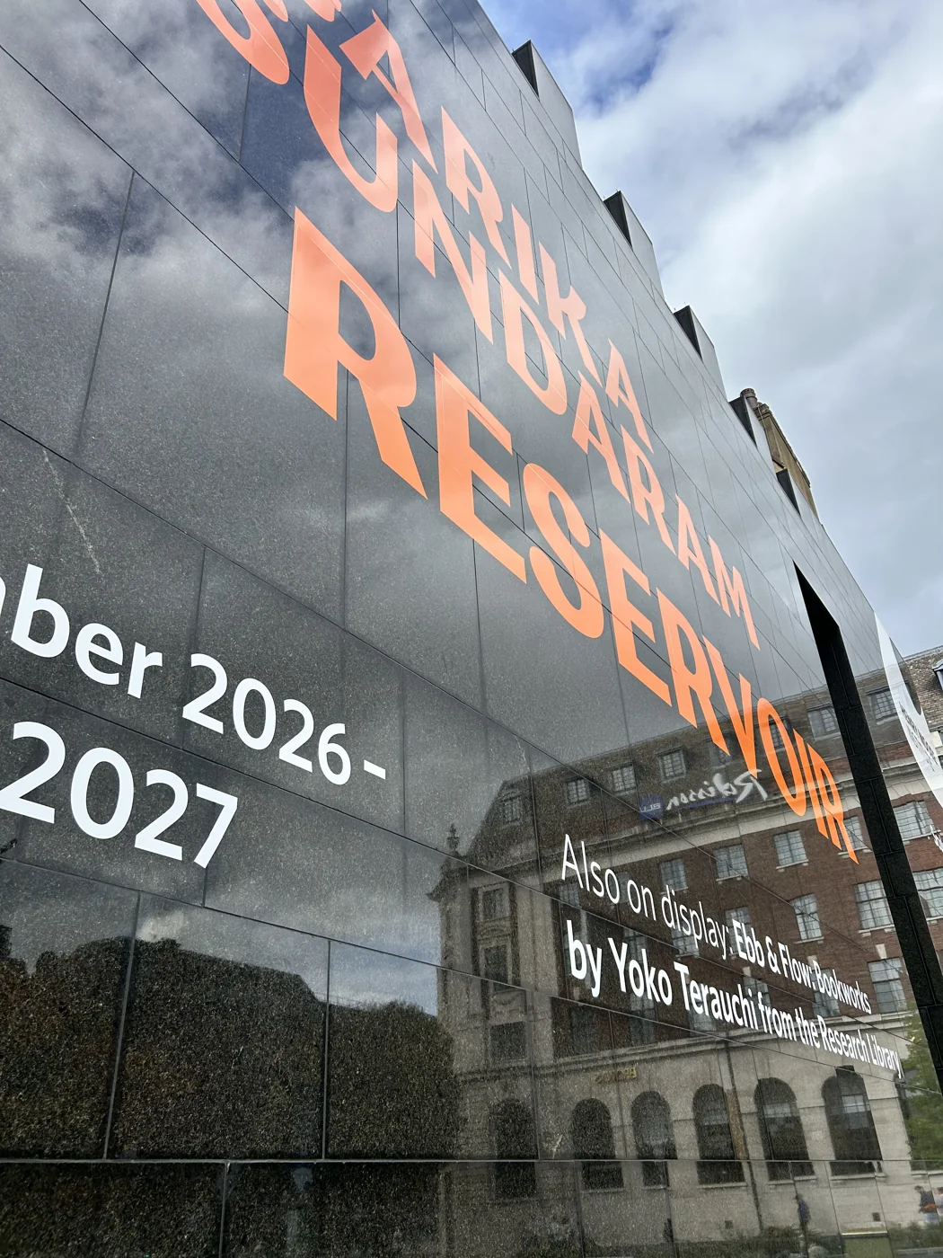 Close view of the glossy orange vinyl letters applied to the dark exterior wall